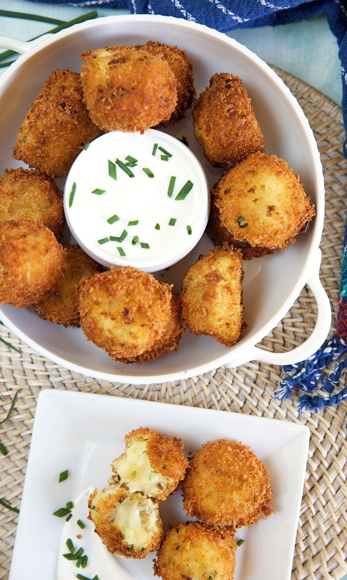 A bowl full of croquettes sits next to a plate with several croquettes.