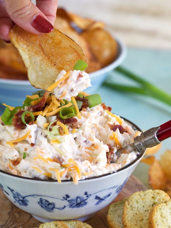 A potato chip is scooping up a small dollop of million dollar dip.