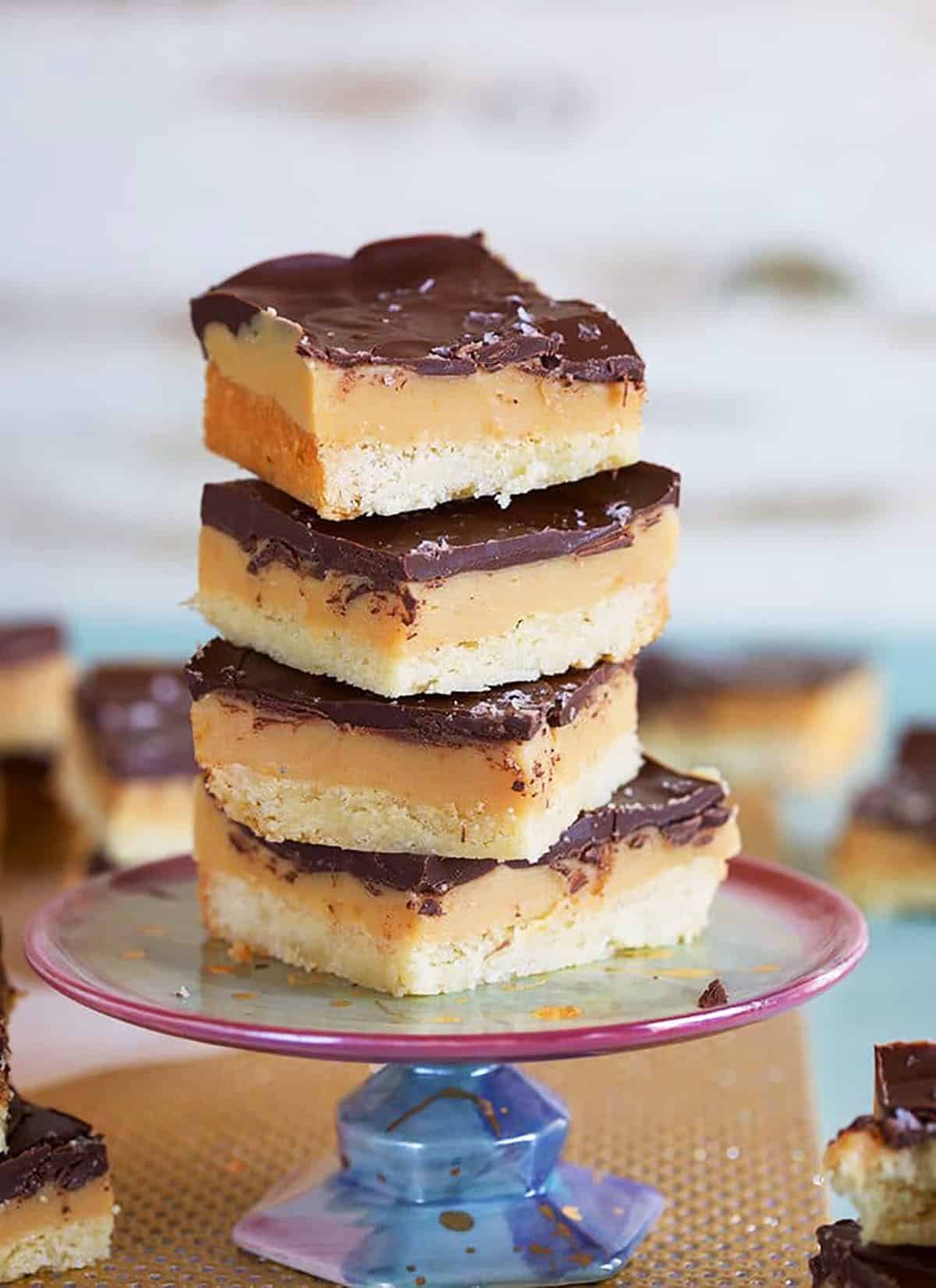 Stack of 4 Millionaire Shortbread Bars on a cupcake stand.