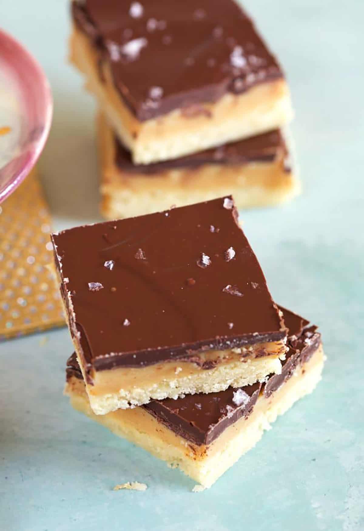Millionaire Shortbread Bars stacked on a blue background.