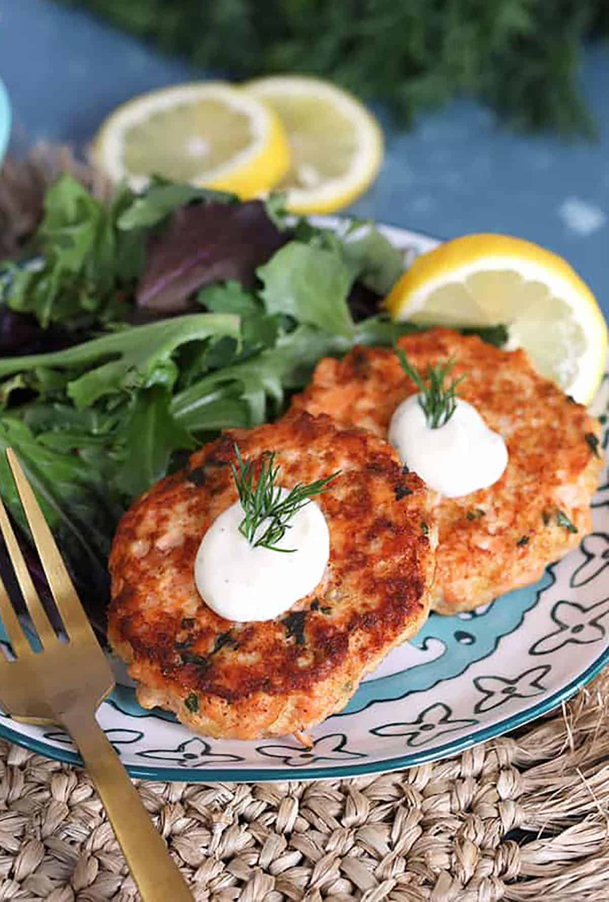 Salmon Cakes recipe with Lemon Dill Sauce on a plate on a wicker placemat