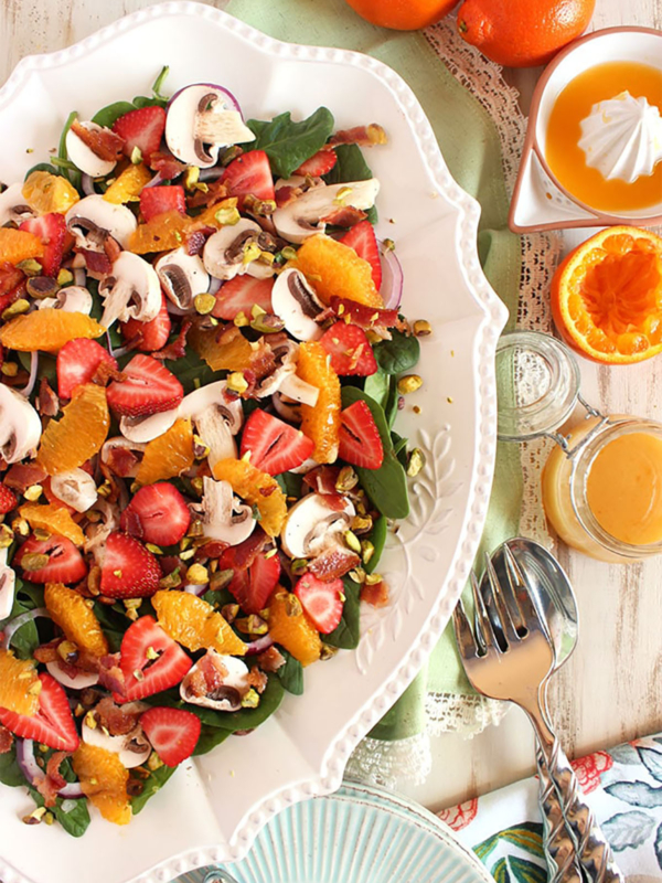 Overhead shot of strawberry spinach salad on a white oval platter.
