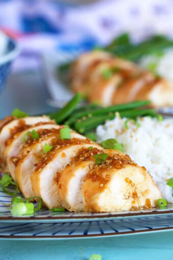 Sliced teriyaki chicken breast on a plate with rice.