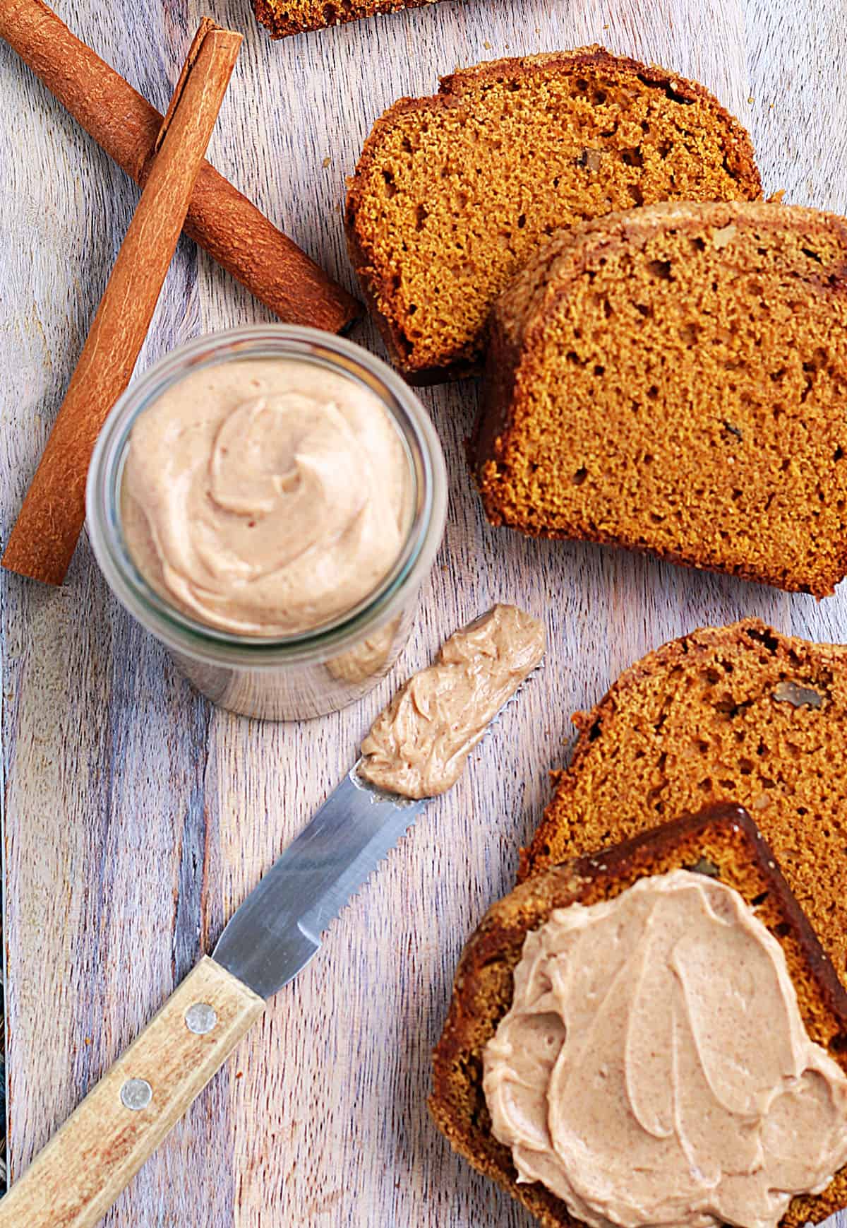 Cinnamon sticks are placed next to a sliced loaf of bread and a jar of Texas Roadhouse butter.