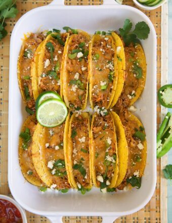 Ten tacos are placed in a large baking dish.