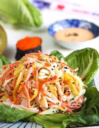 Kani Salad on a bed of lettuce with spicy sauce in the background.