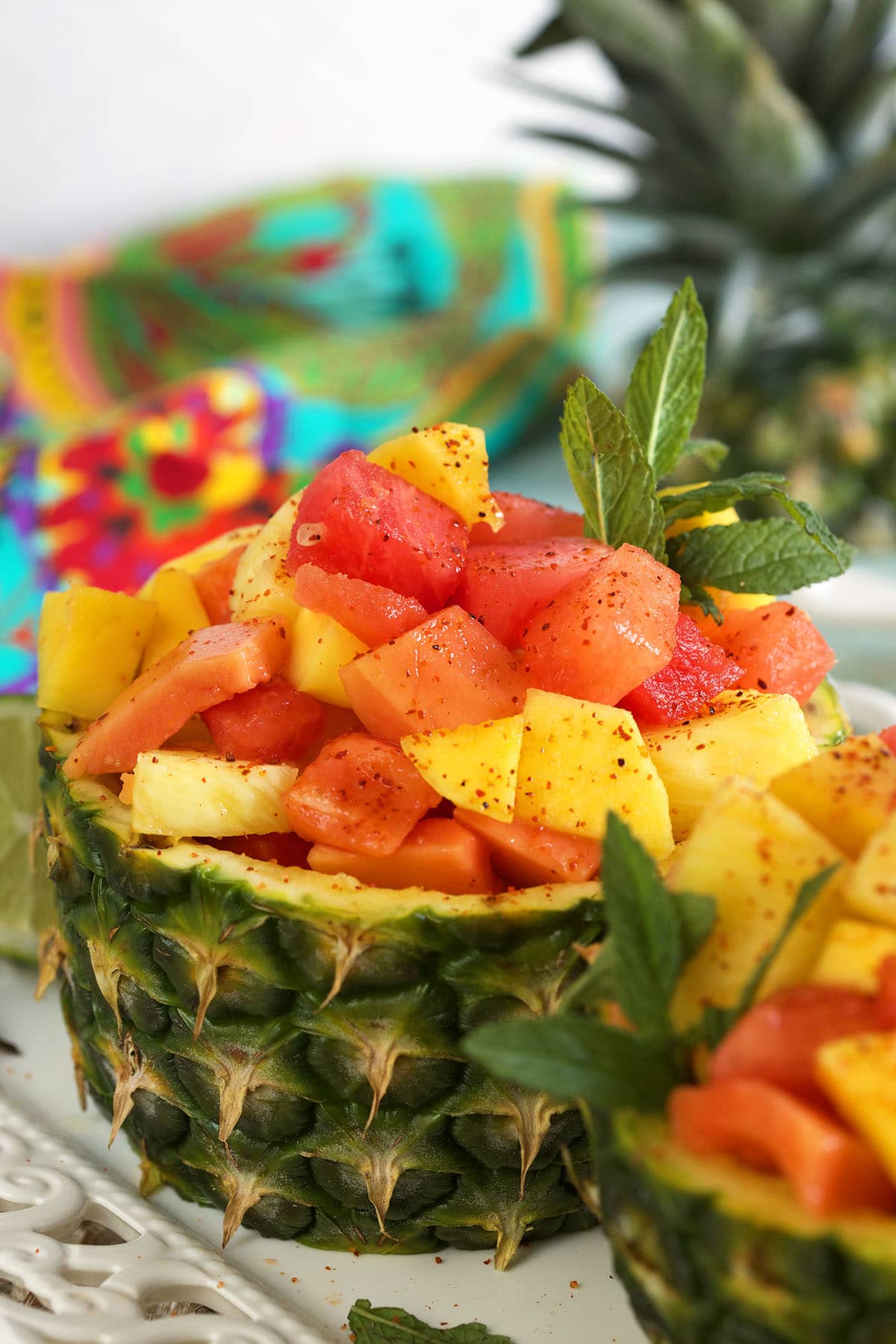 A fruit salad is placed in half of a pineapple.