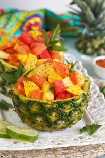 Two pineapple halves are filled with fresh fruit.