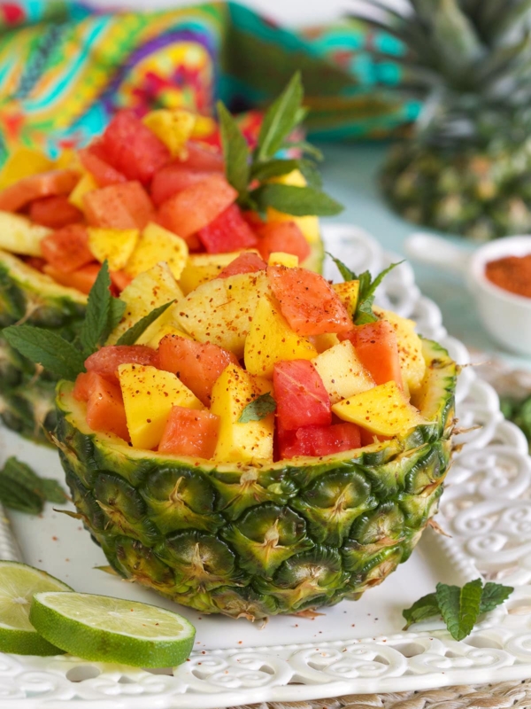 Two pineapple halves are filled with fresh fruit.