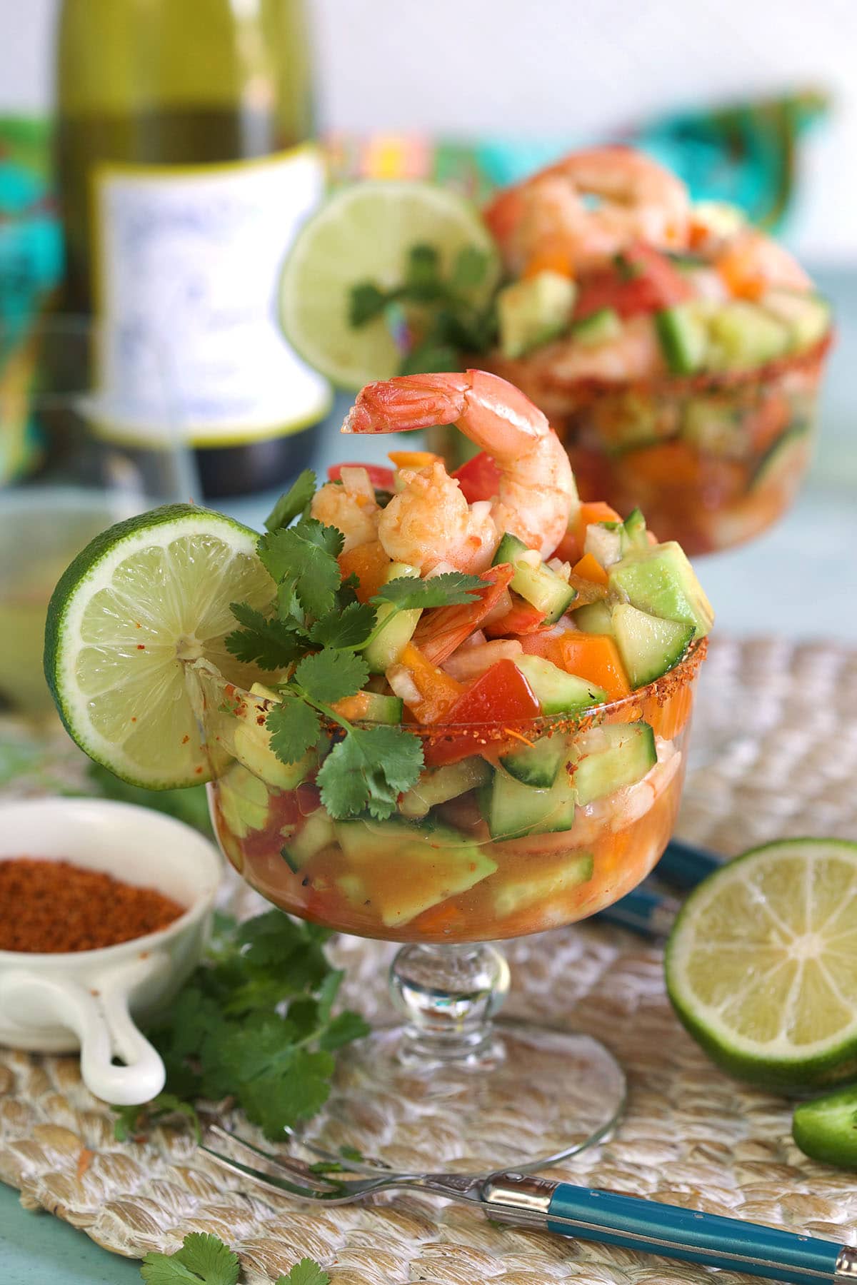 A shrimp cocktail is presented with a slice of lime on the side of the glass.