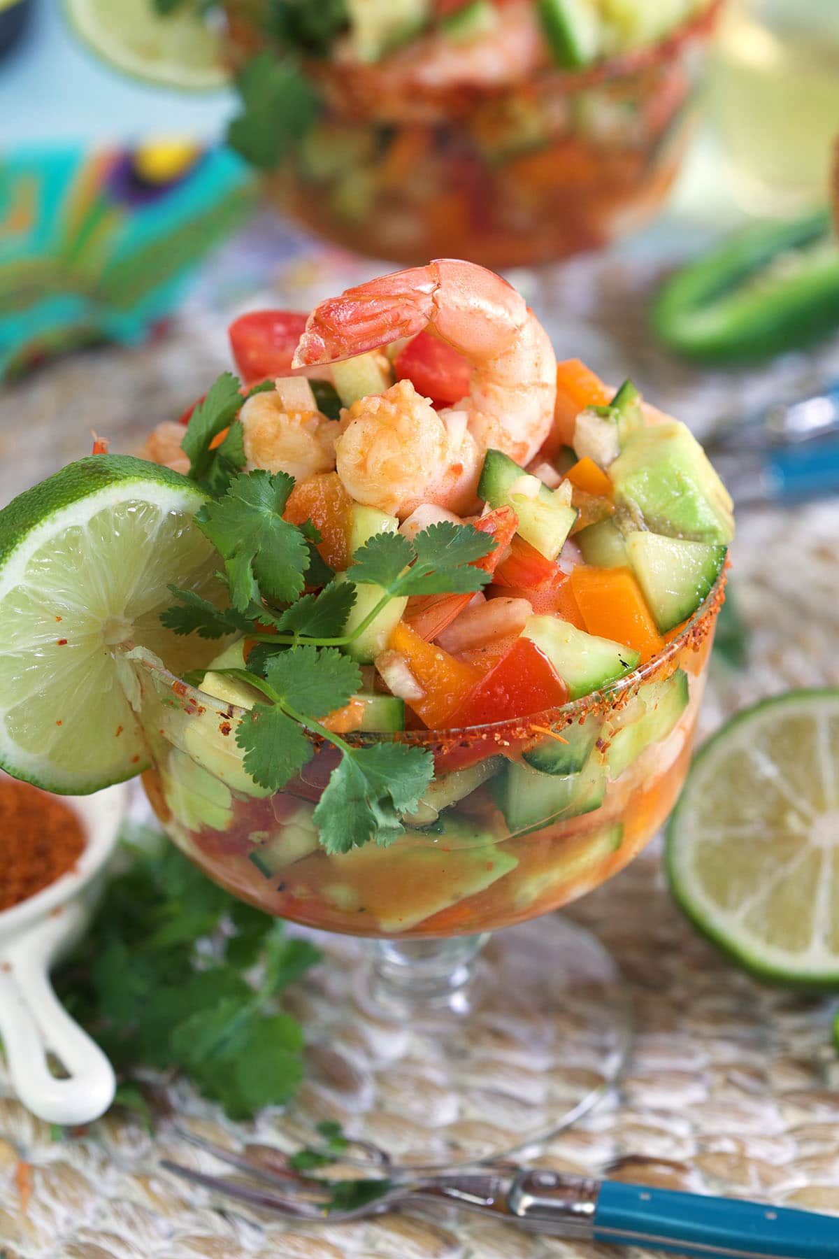 A lime and piece of cilantro garnish a shrimp cocktail.