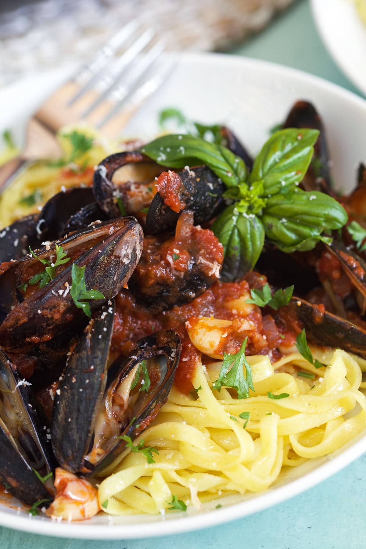 A plate of noodles is covered in marinara tossed mussels. 