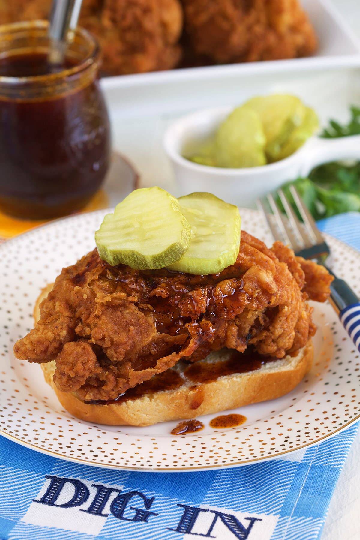 Pickles are placed on top of a fried chicken sandwich. 