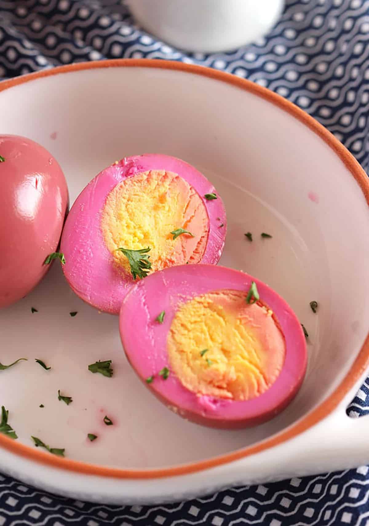 Beet Pickled Egg cut in half on a white dish with parsley sprinkled on it.