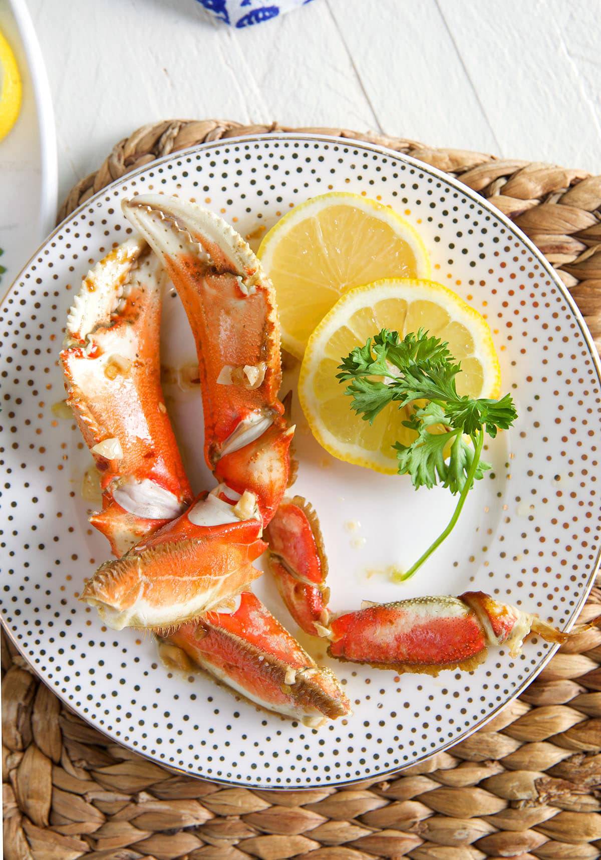 Two crab legs have been placed on a plate with lemon slices.