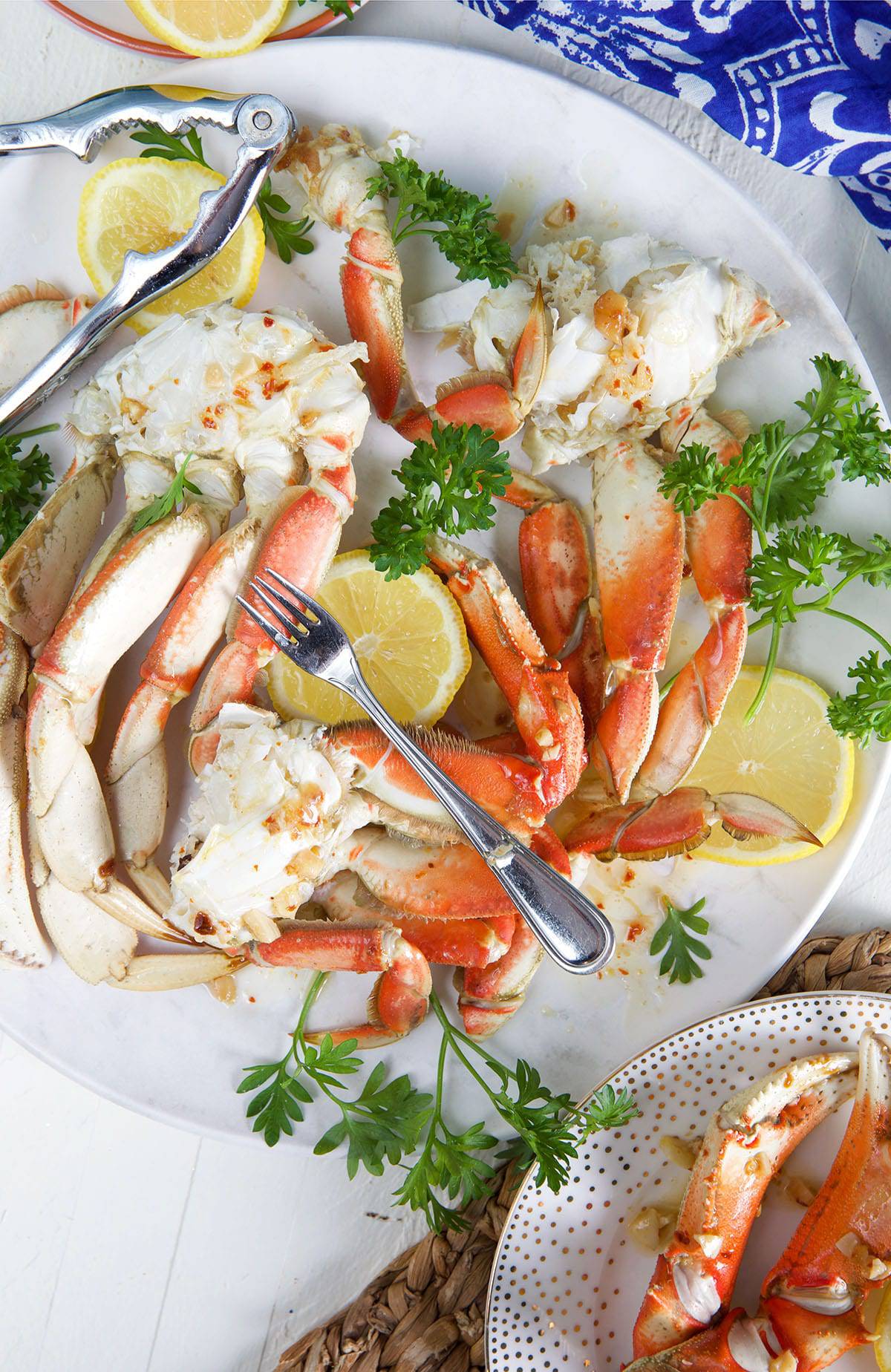 Several serving utensils are placed on a plate of crab legs.
