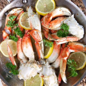 A pot of crab legs is filled also with lemon and herbs.