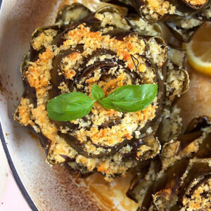 Close up of one stuffed artichoke topped with a basil sprig.