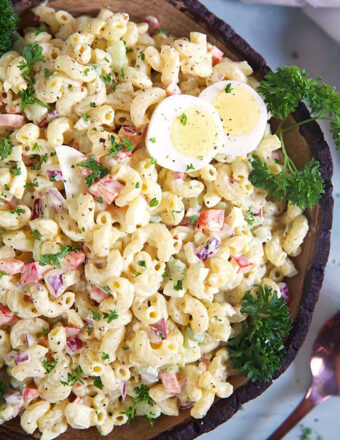 Overhead shot of amish macaroni Salad in a wooden bowl on a blue background.