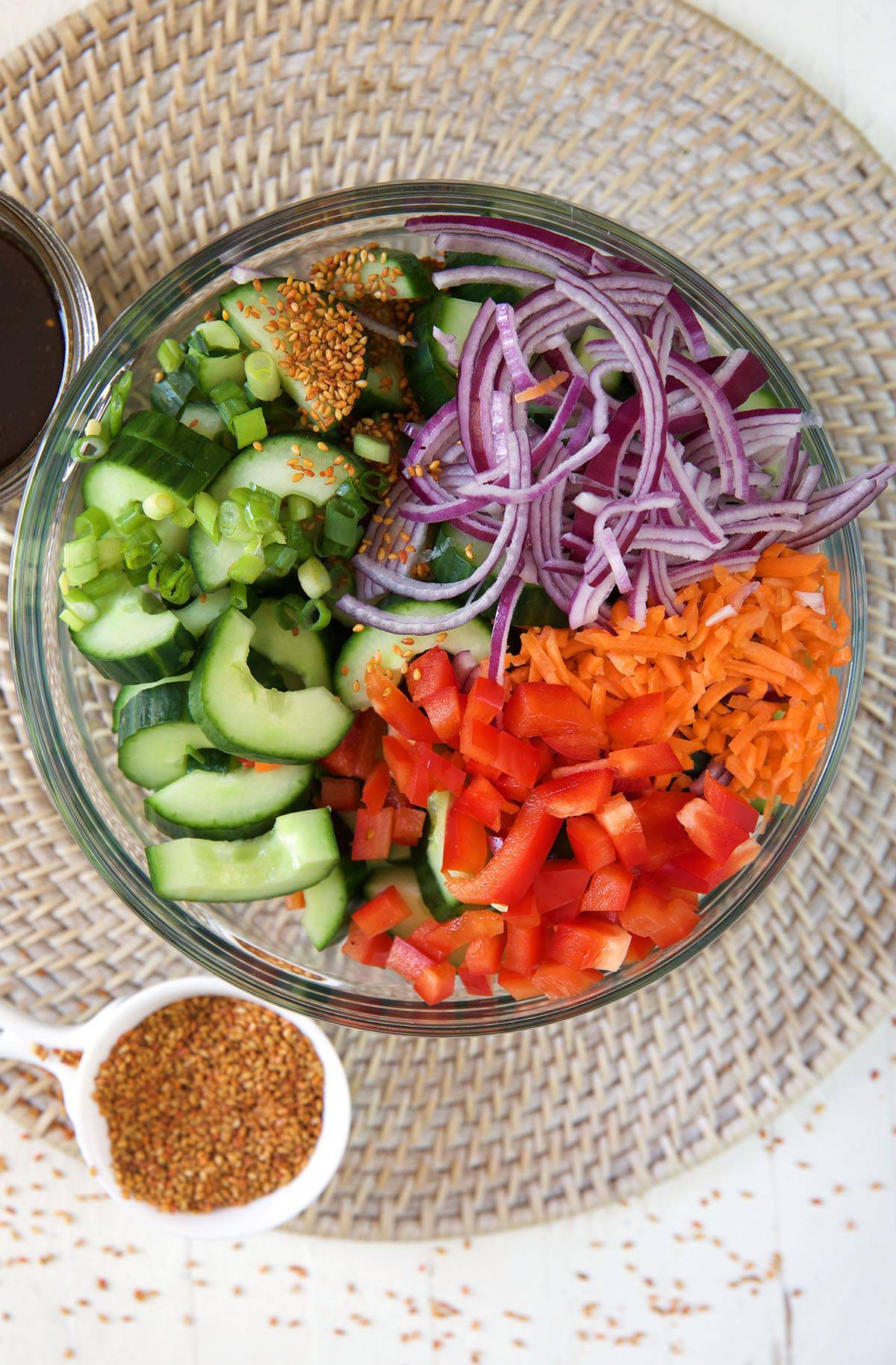 All of the ingredients for cucumber salad are in a large glass bowl. 