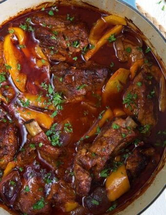 A pot is filled with ribs, peppers and sauce.