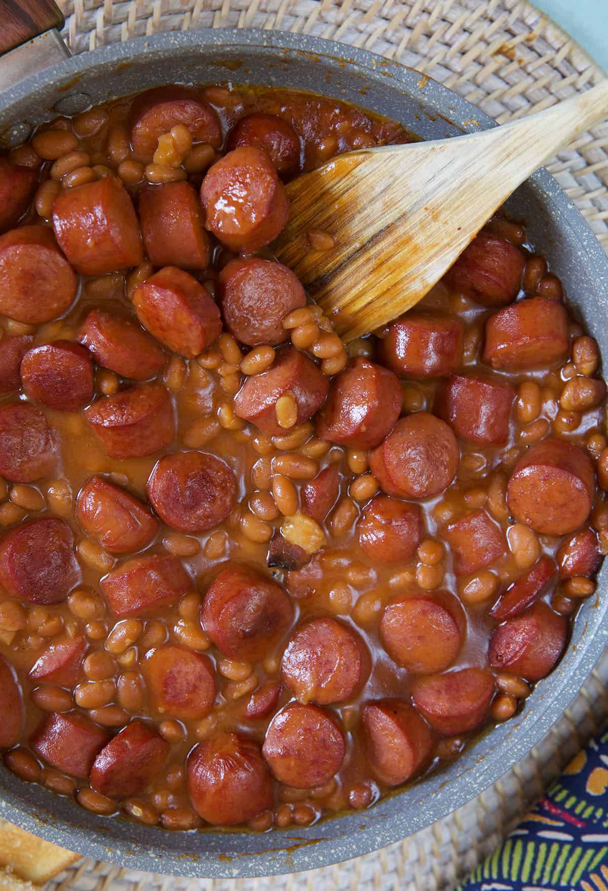 A large skillet contains cooked beanie weenies.