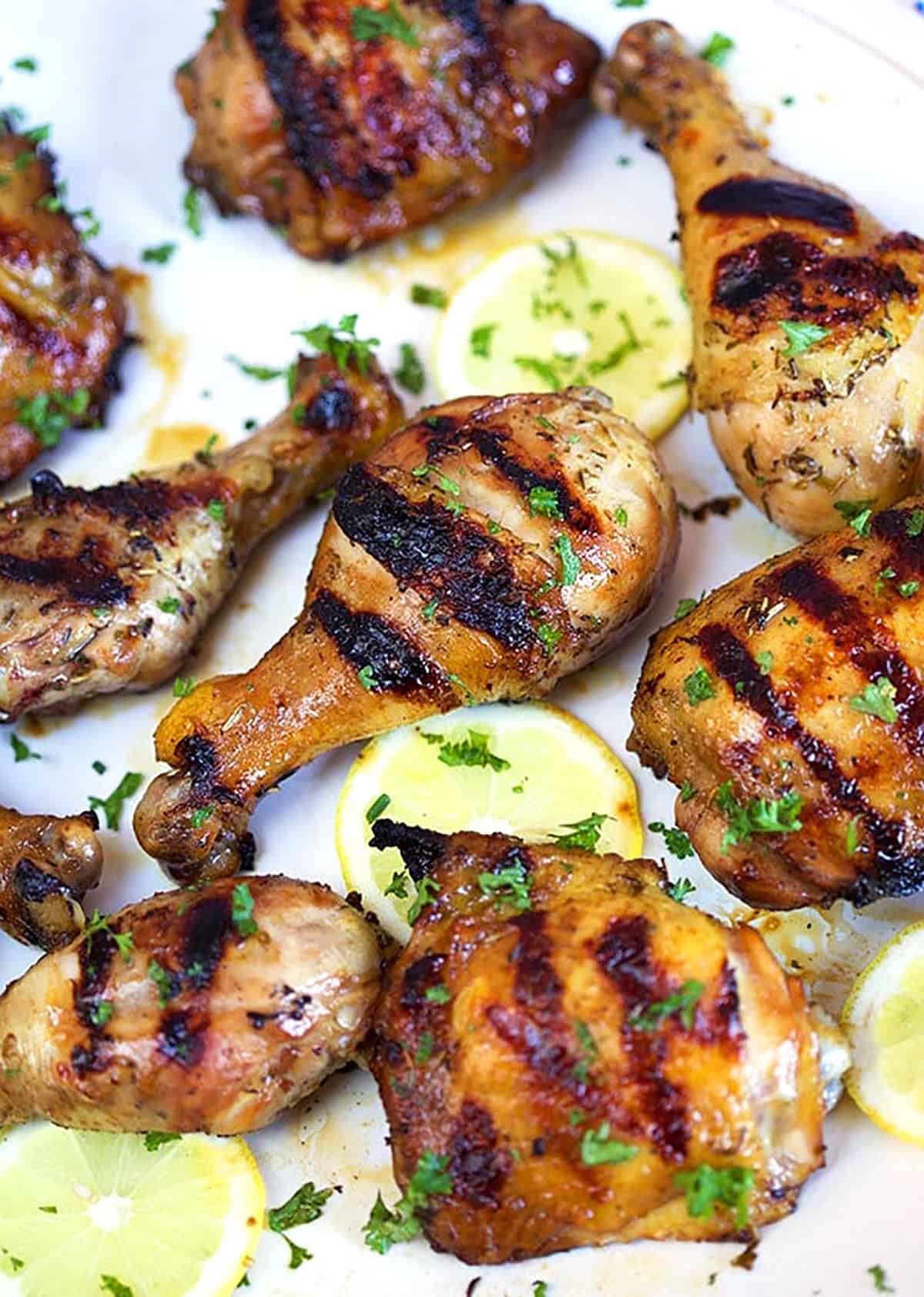 Grilled chicken on a white platter with lemons and parsley