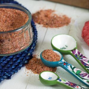 Small measuring spoons are placed next to a jar of seasoning.