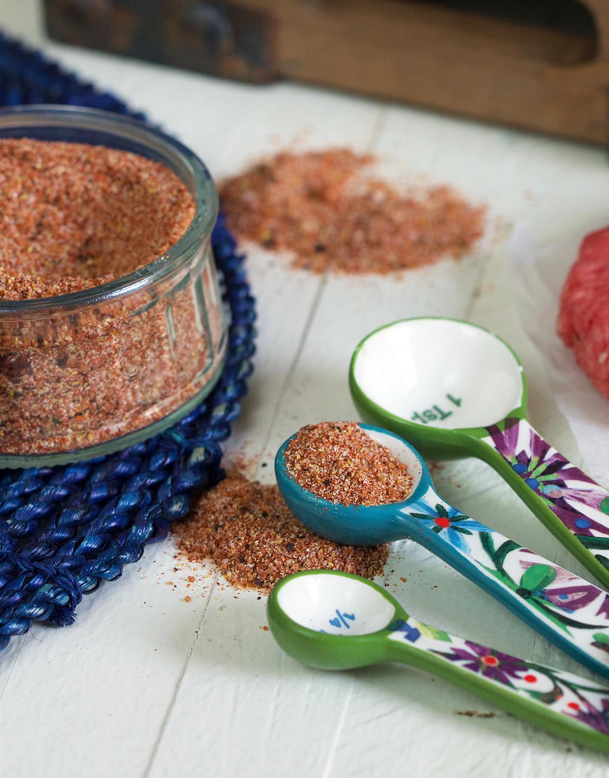 Small measuring spoons are placed next to a jar of seasoning.