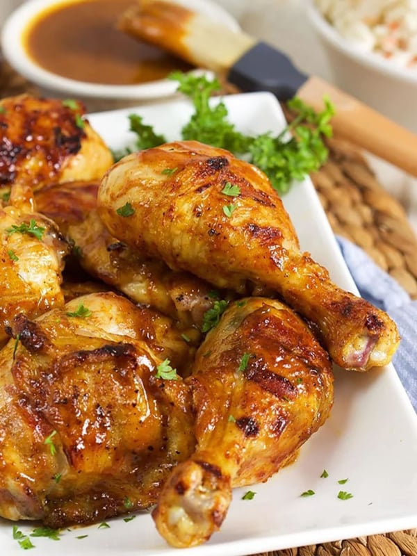 Carolina Gold BBQ Chicken on a white platter with a bowl of Carolina Gold bbq sauce in the background.