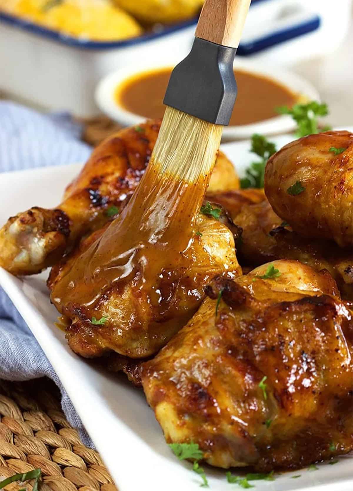 a basting brush coating bbq chicken with Carolina Gold sauce.