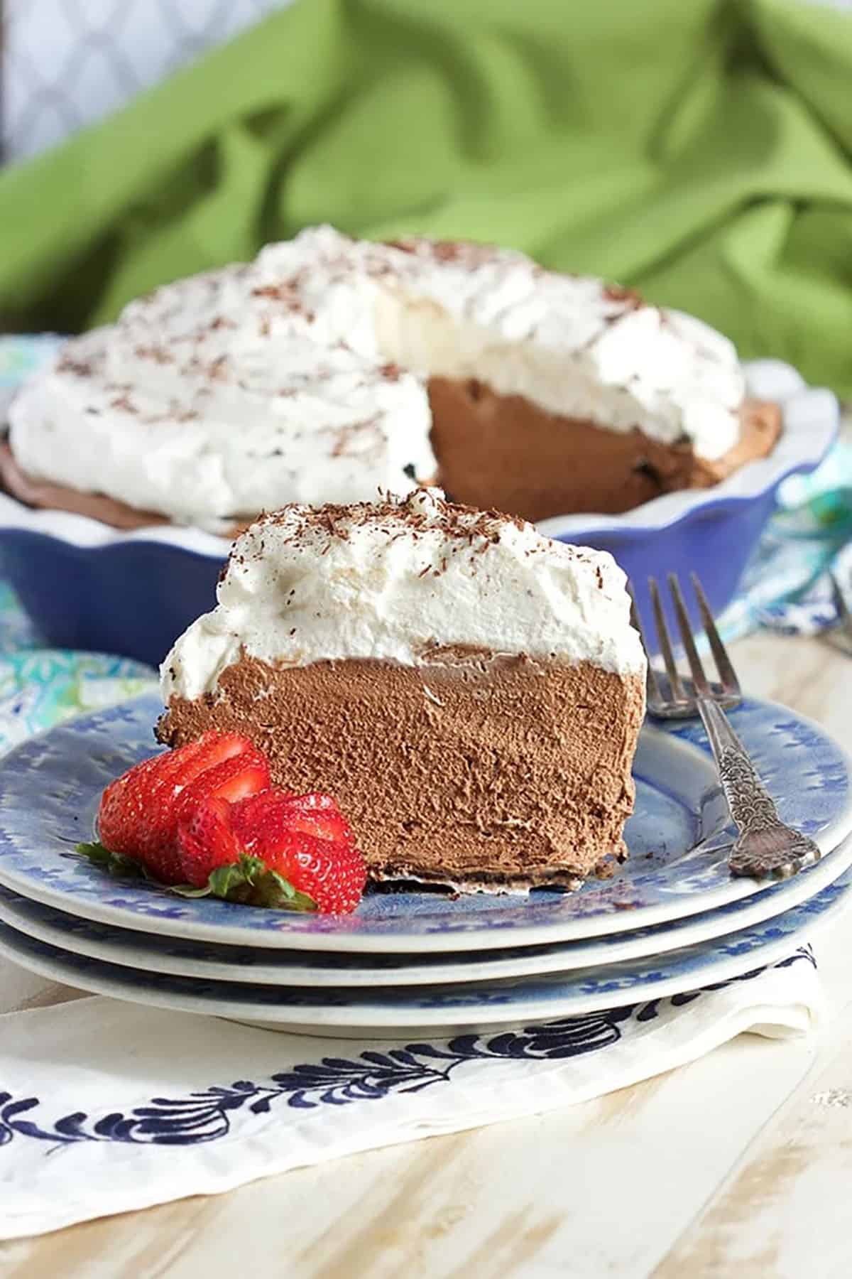 Chocolate Mousse Pie slice on a blue plate with a whole pie in the background.