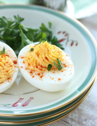 Deviled egg on a plate with paprika and parsley sprinkled on top.