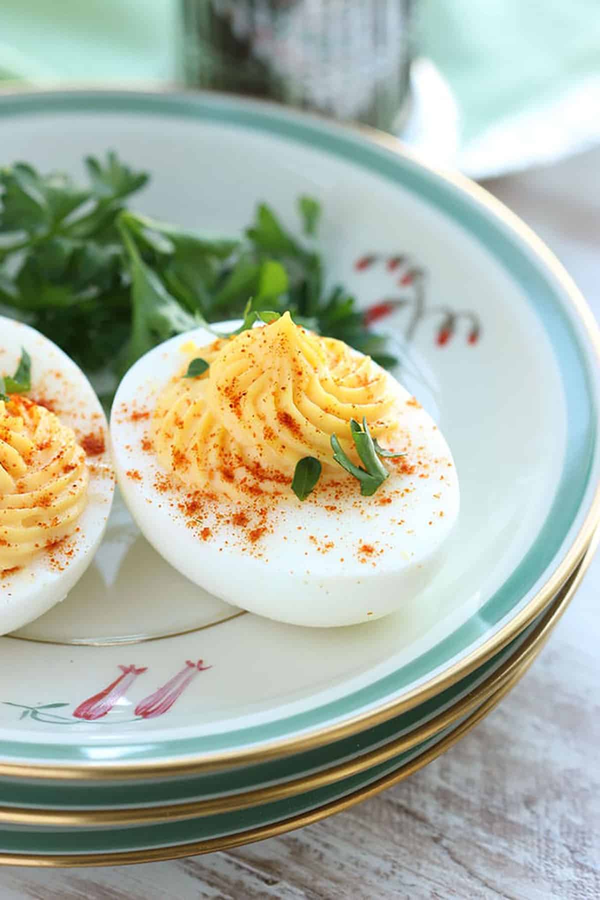 Deviled egg on a plate with paprika and parsley sprinkled on top.
