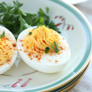 Deviled egg on a side plate with paprika sprinkled on top