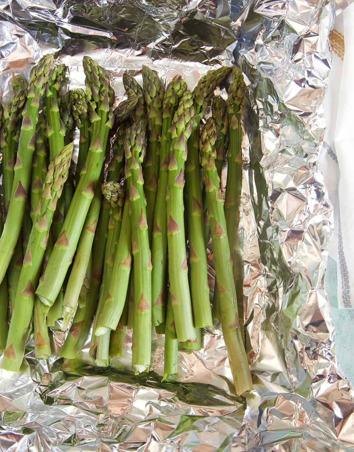 Uncooked asparagus is placed on foil. 