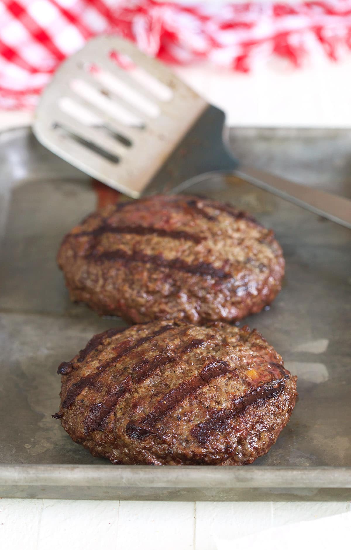 Burgers are fully cooked and placed on a baking sheet.