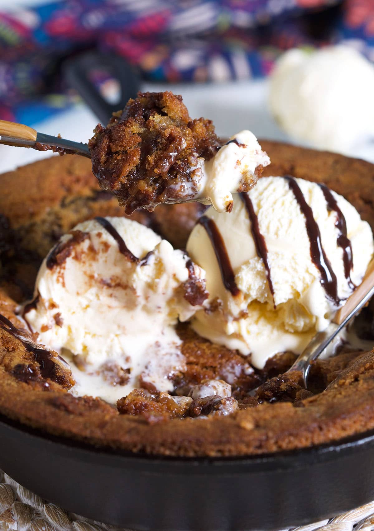 A spoon is lifting a bite of pizookie from a skillet.