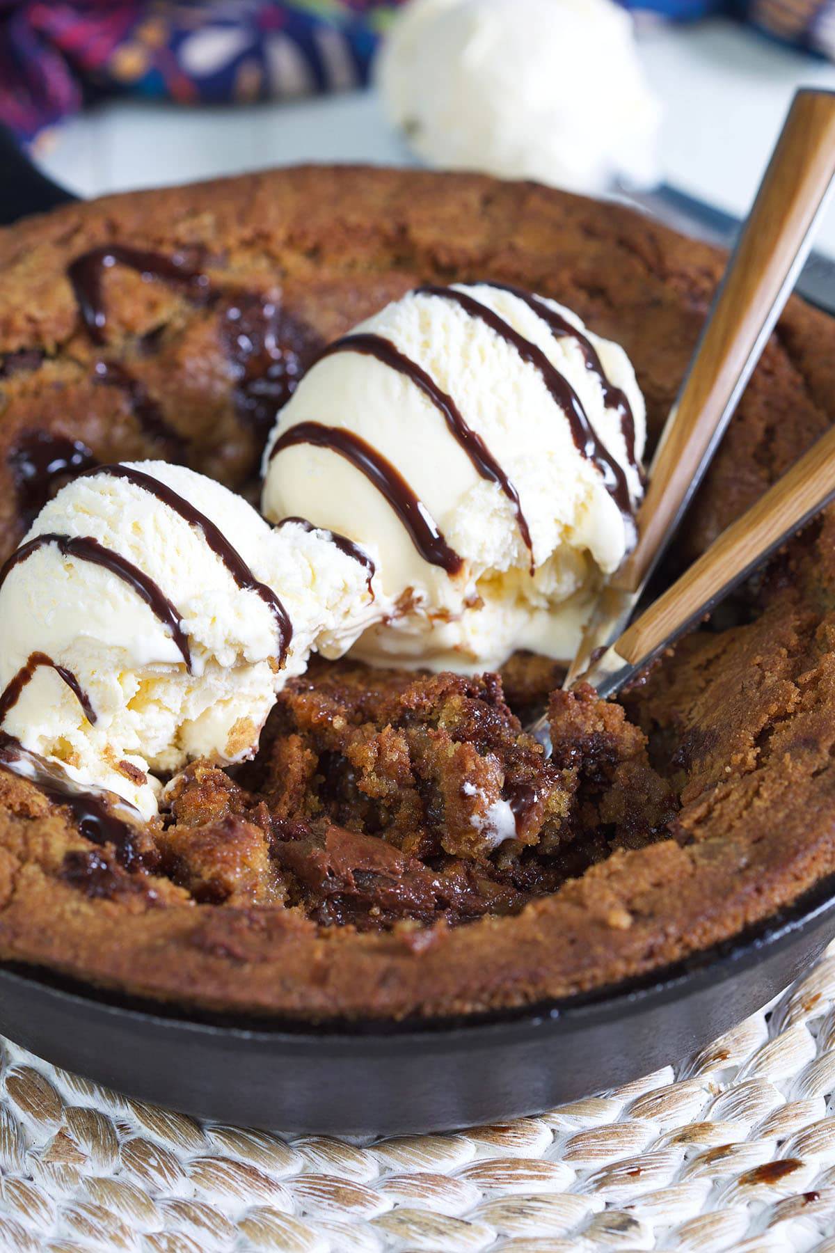 Two spoons are digging into a pizookie. 