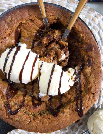 Two dollops of vanilla ice cream are placed on top of a warm pizookie.