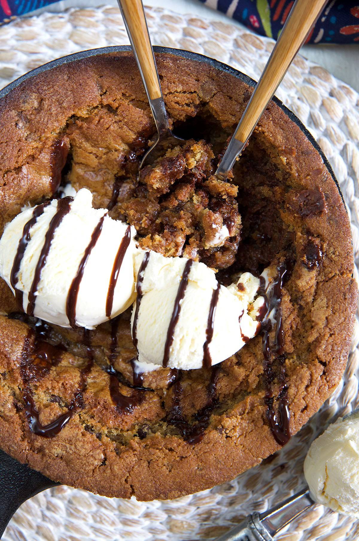 Two dollops of vanilla ice cream are placed on top of a warm pizookie. 
