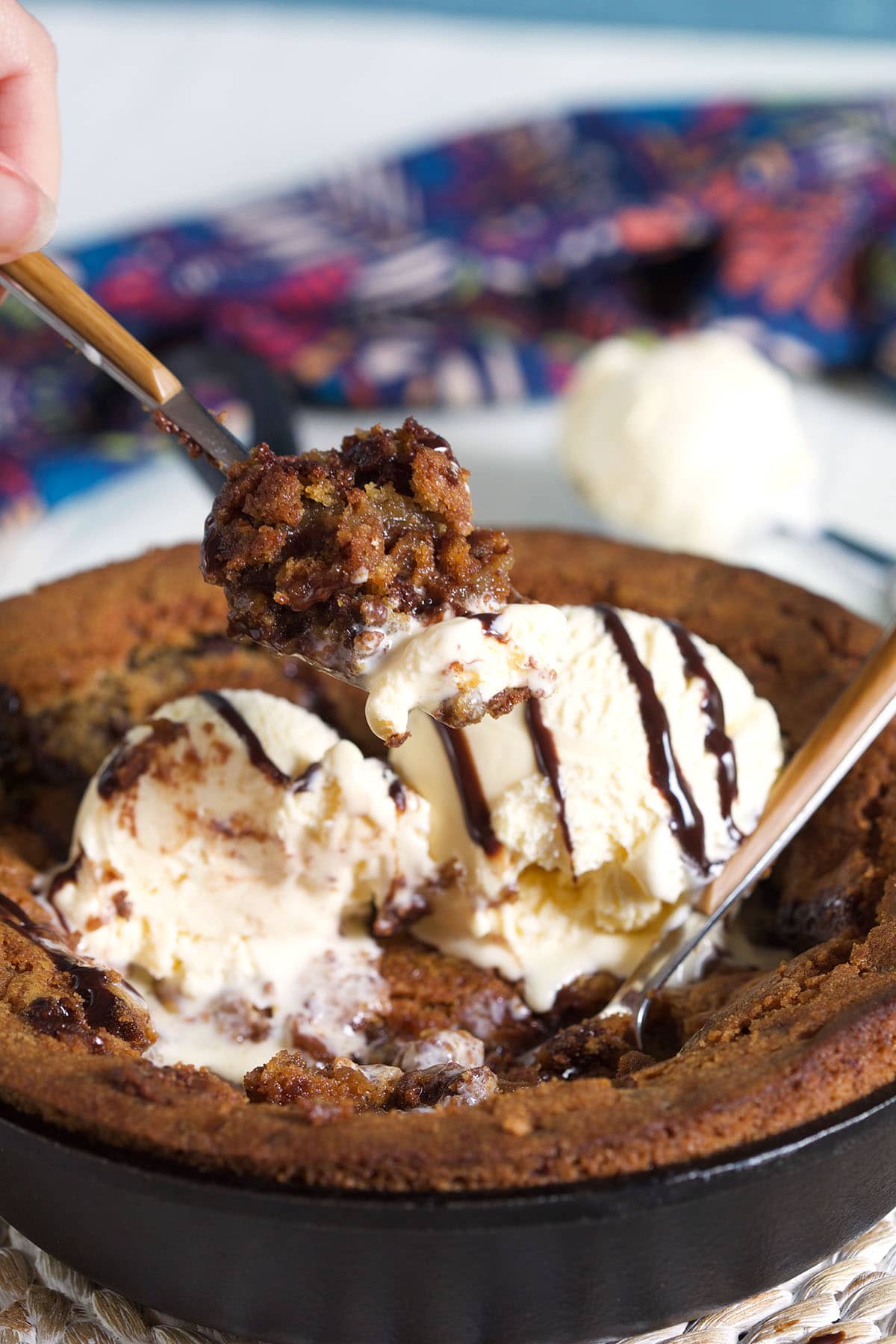 A bite of pizookie is being lifted from the warm skillet. 