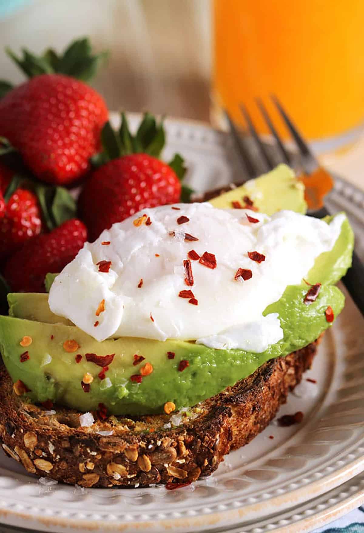 Poached eggs on avocado toast on a white plate.