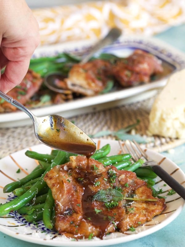 Veal Saltimbocca with sauce being drizzled over top with a spoon.