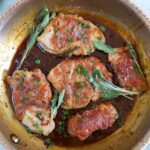 Veal Saltimbocca in a skillet with fresh sage.