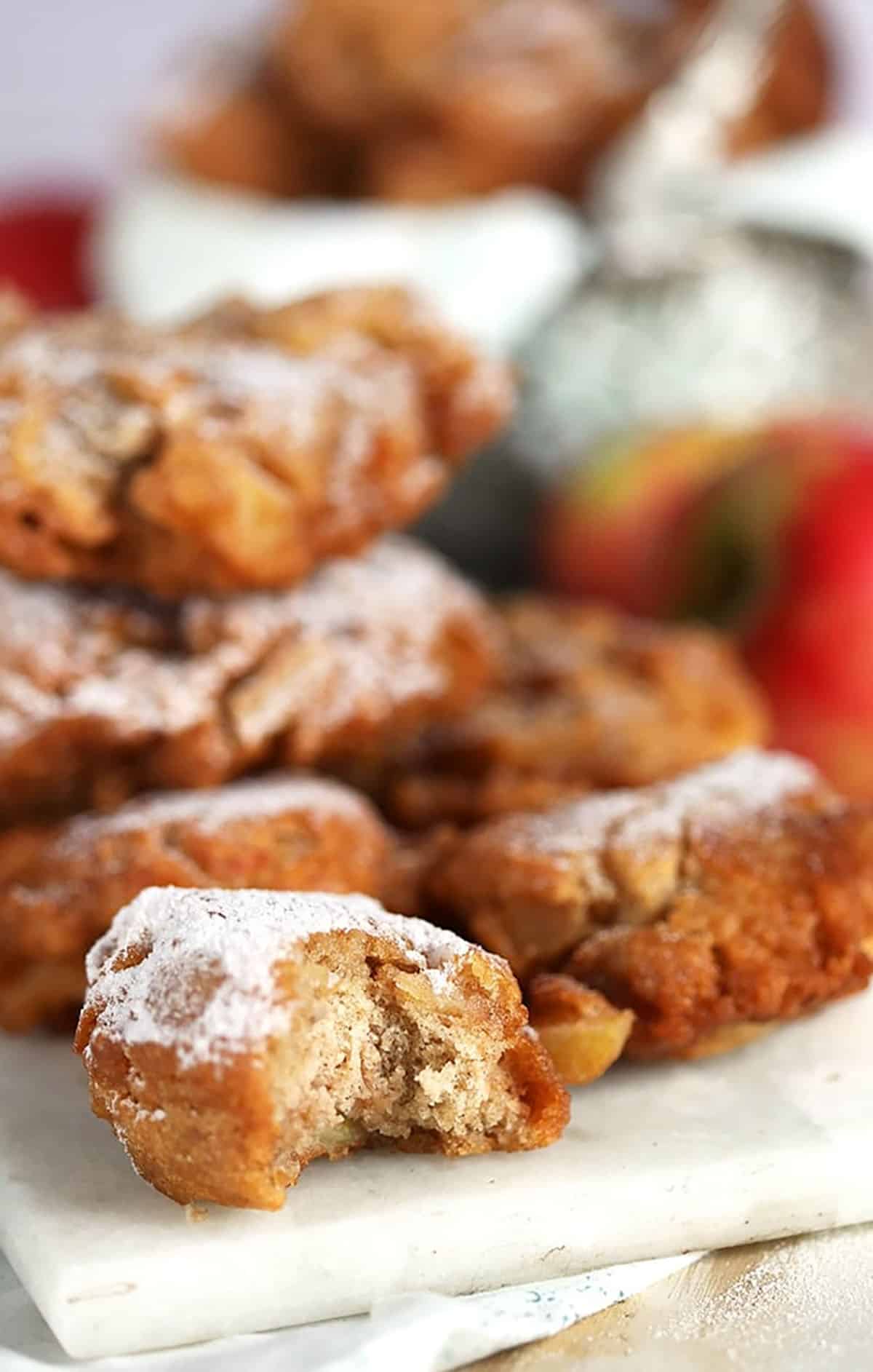 Apple fritters with a bite taken on a marble platter 