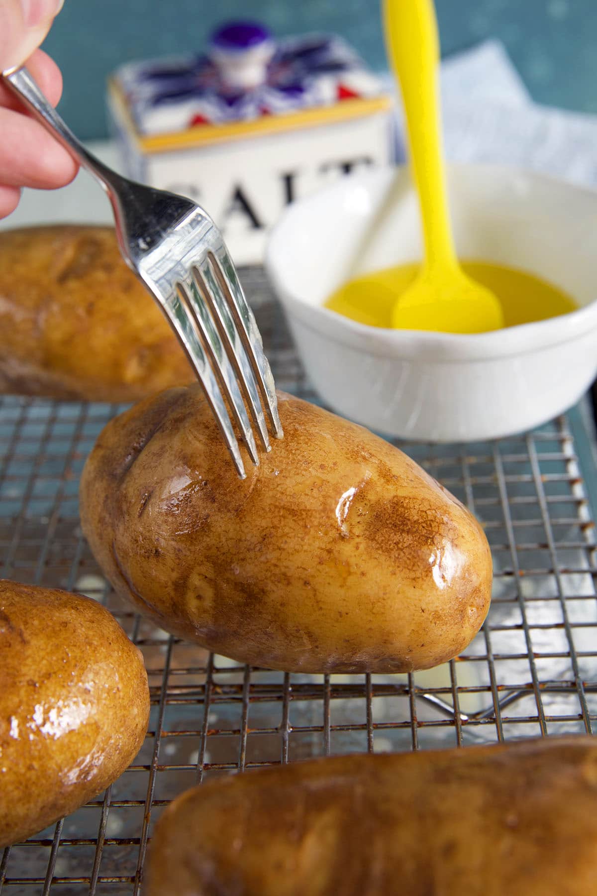 A fork is poking holes into a potato. 