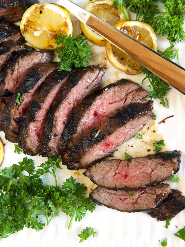 Slices of steak are on a white plate.