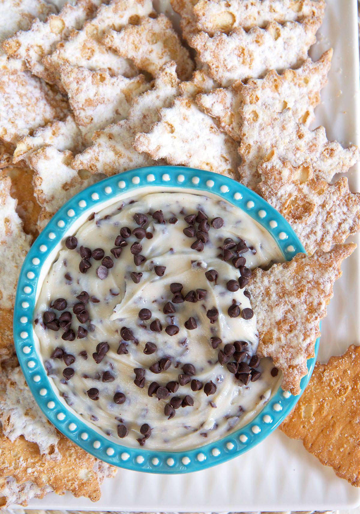 Many cannoli shells are placed around a small bowl. 