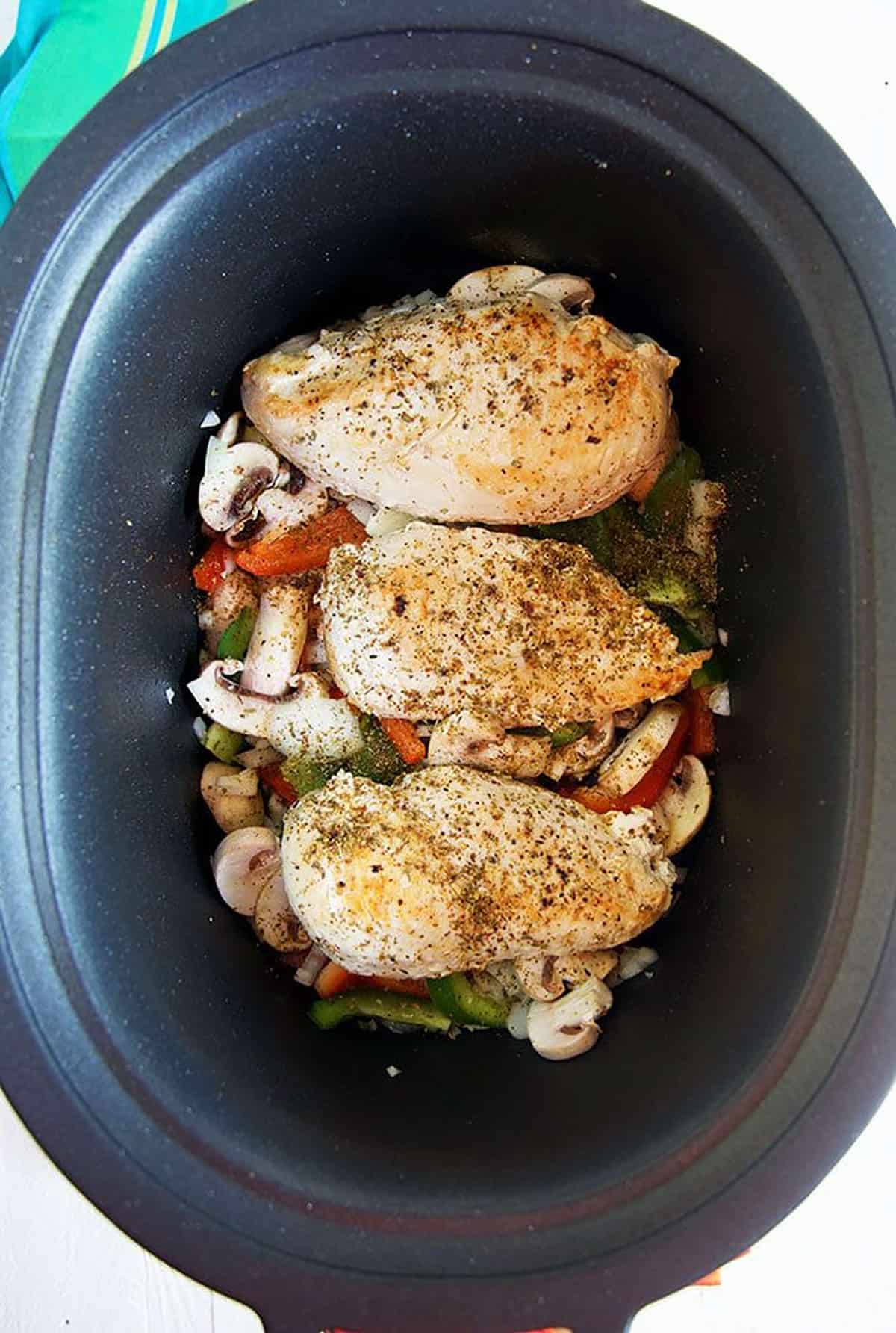 Chicken on vegetables for chicken cacciatore, step two of slow cooker chicken cacciatore.